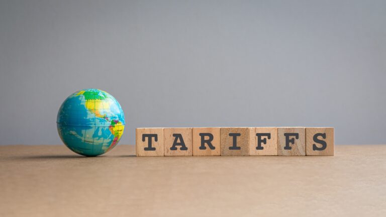 Miniature globe next to scrabble blocks that spell tariffs.